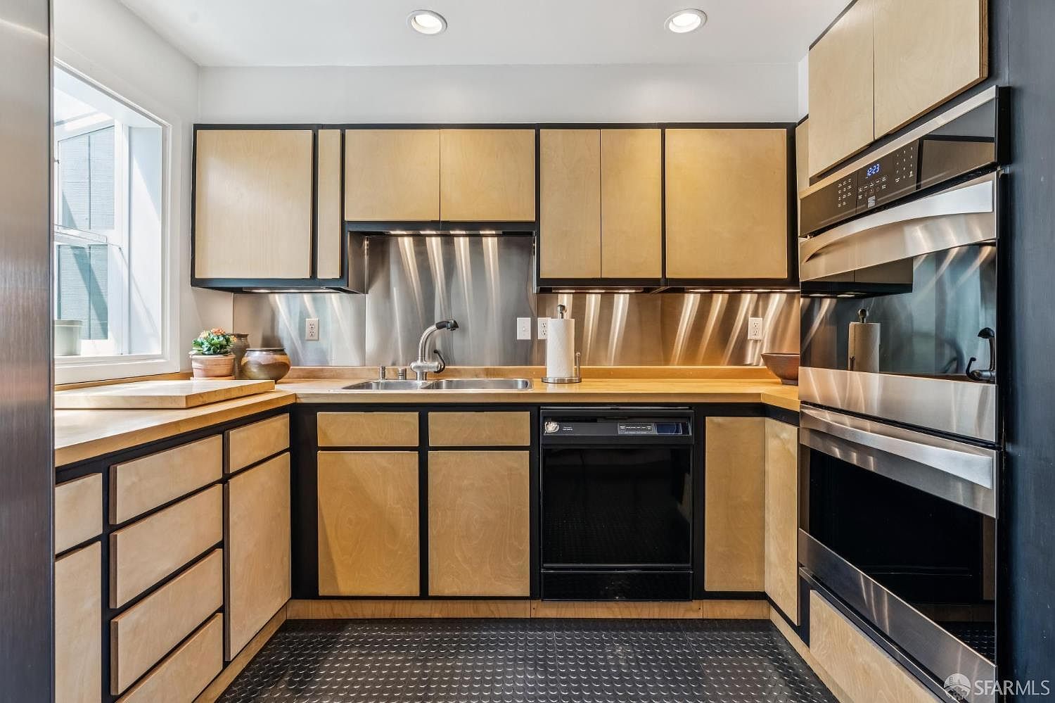 The kitchen at 138 Clifford Terrace with birch cabinetry, butcher-block counters, stainless backsplash, and double wall ovens